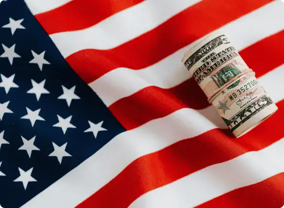 Gerollte US-Dollarscheine auf einer amerikanischen Flagge